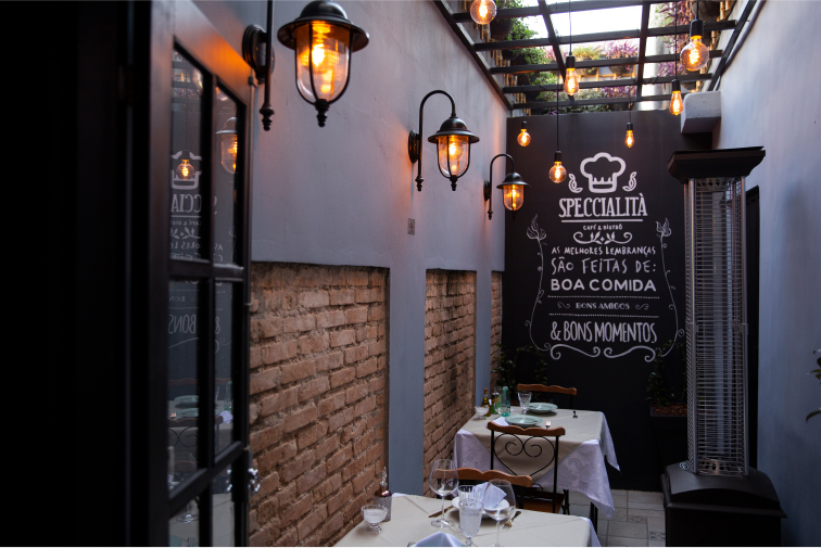 Ambiente Bistro escuro com luzes de tons laranjas e com mesas e cadeiras