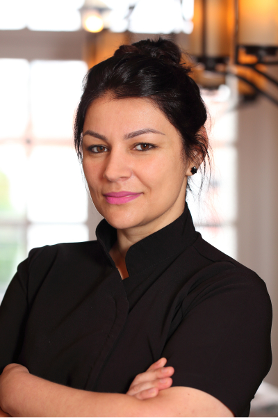 Chef Estela Maris segurando dois pratos prontos em um restaurante